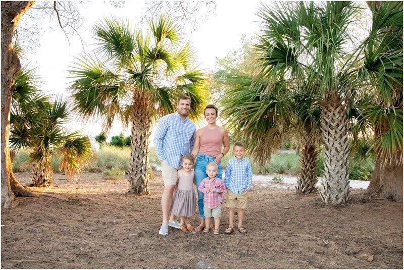 A family photo with three little ones under five with palm trees in the background