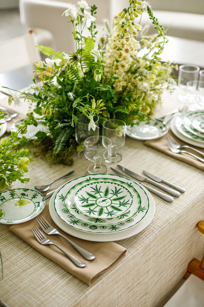 Wedding reception dinner table with green and white Sultan's Garden dishware and sleek silver flatware