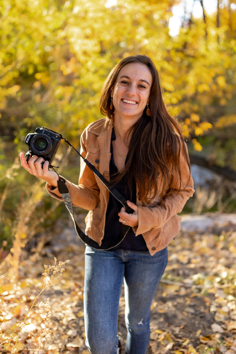 A photographer shows off her Nikon camera at a photoshoot in the fall.