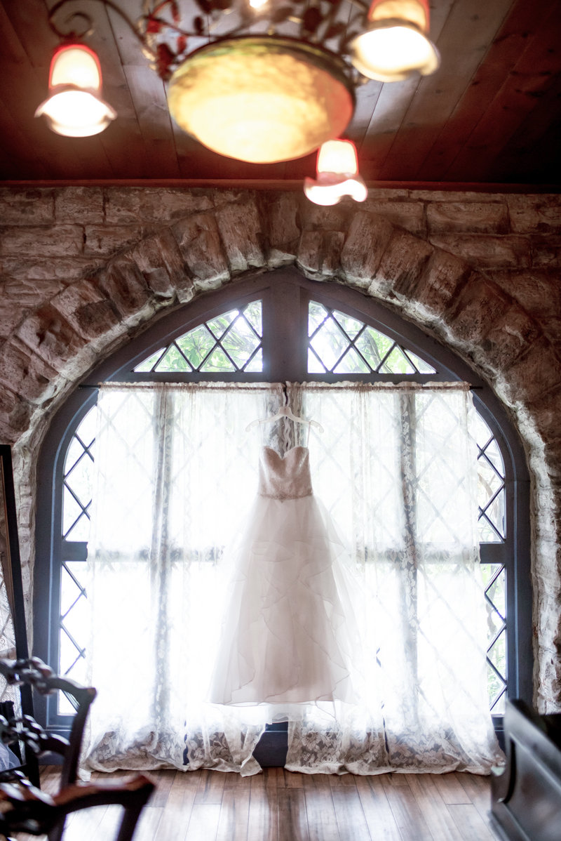 Backlit photo of a wedding dress hung in a castle window