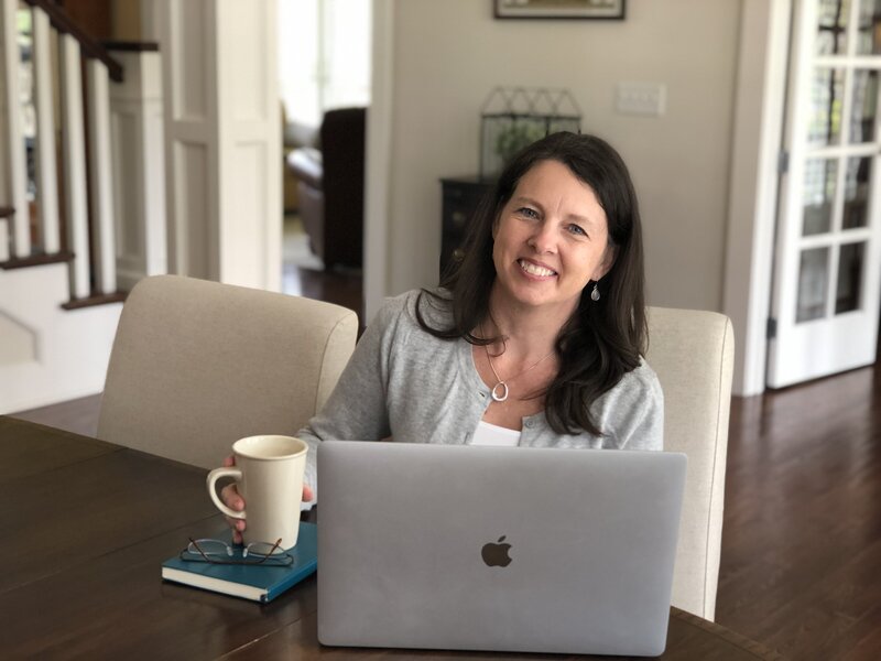 Rachel Sanford working at table with mug and laptop