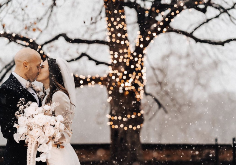 Winter wedding couple with snow and tree with fairy lights