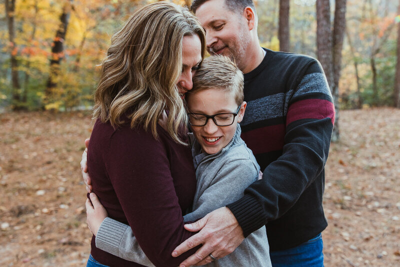 Portrait of mother, son and dad hugging at the park in Farmington, Missouri. 