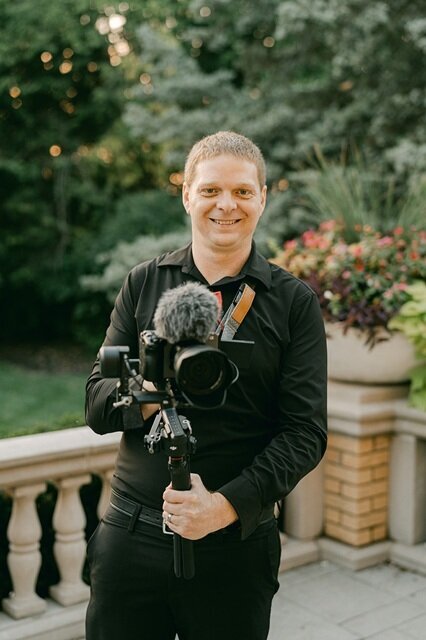 Henry Clark, cinematic videographer in Indianapolis, holding a camera at a wedding venue.