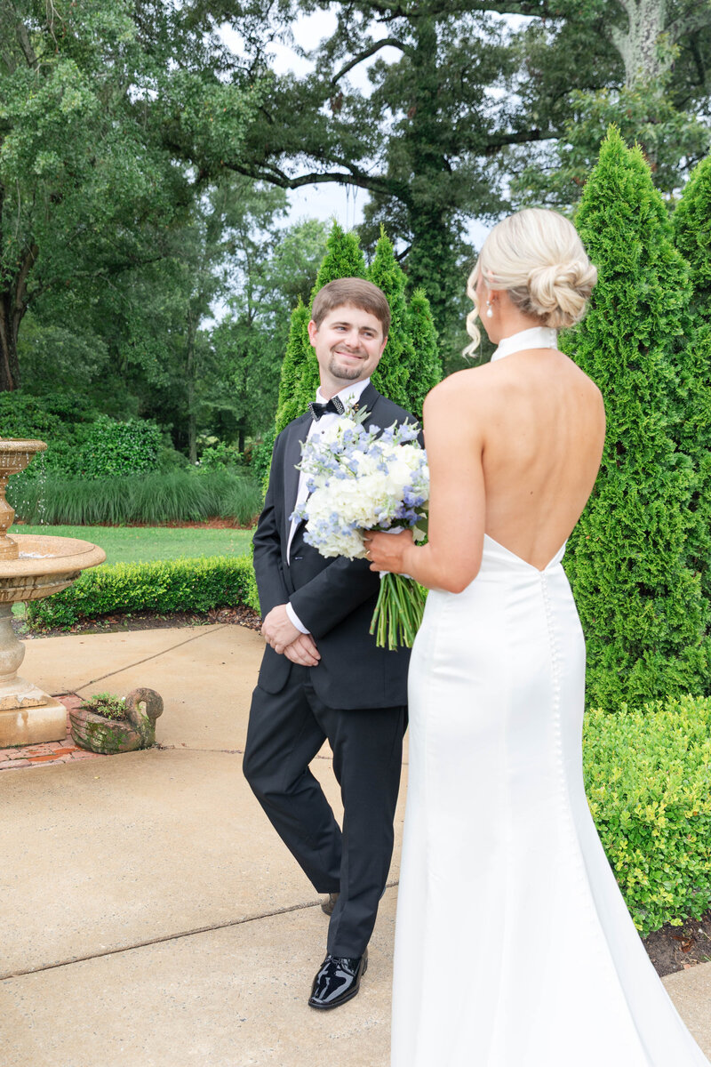 Groom smiling at bride during emotional first look on wedding day in garden setting