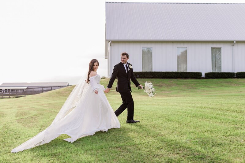 Couple walking in a field at their wedding at The Farmhouse