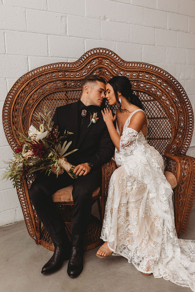 Engagement photo with couple snuggling on peacock chair in studio