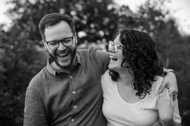 A candid moment of a couple laughing during their engagement session, beautifully portrayed in a black and white photograph.