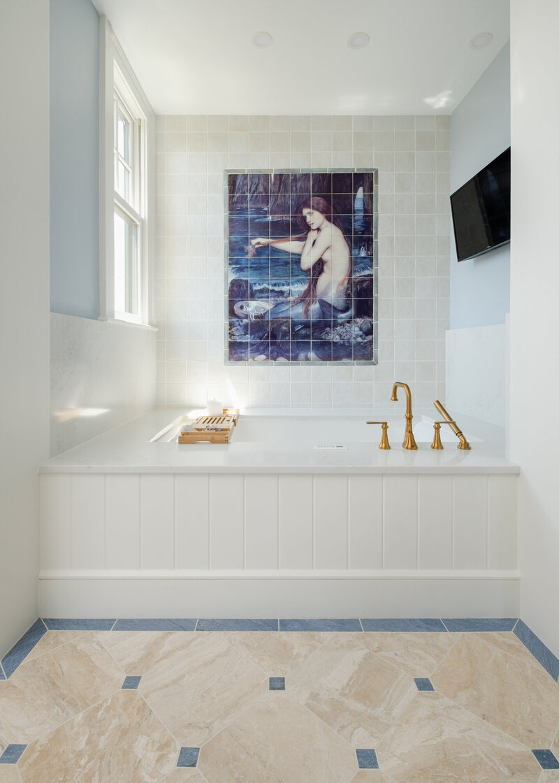 Serene coastal bathroom from The Carolina project by Dwelling Place Interiors, featuring soft neutral tones, elegant tilework, a spa-like soaking tub, and natural light. A perfect blend of warmth and sophistication for a tranquil retreat.