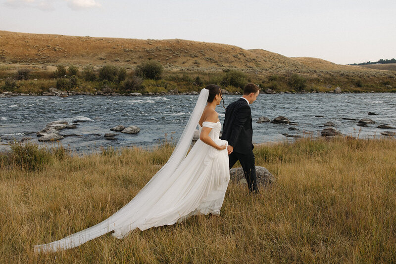 bride and groom walking along banks of the madison river in big sky montana