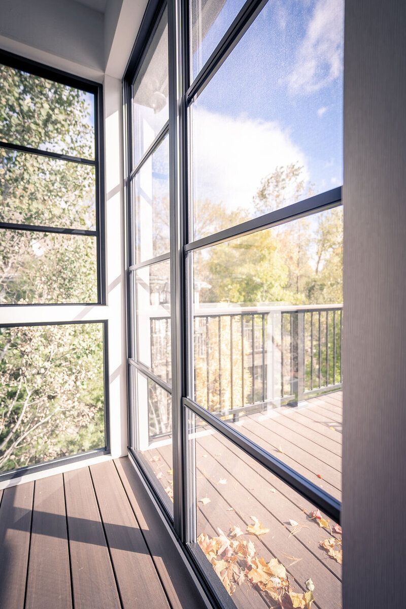 Floor-to-ceiling vinyl windows on a screened-in room on a composite deck. 