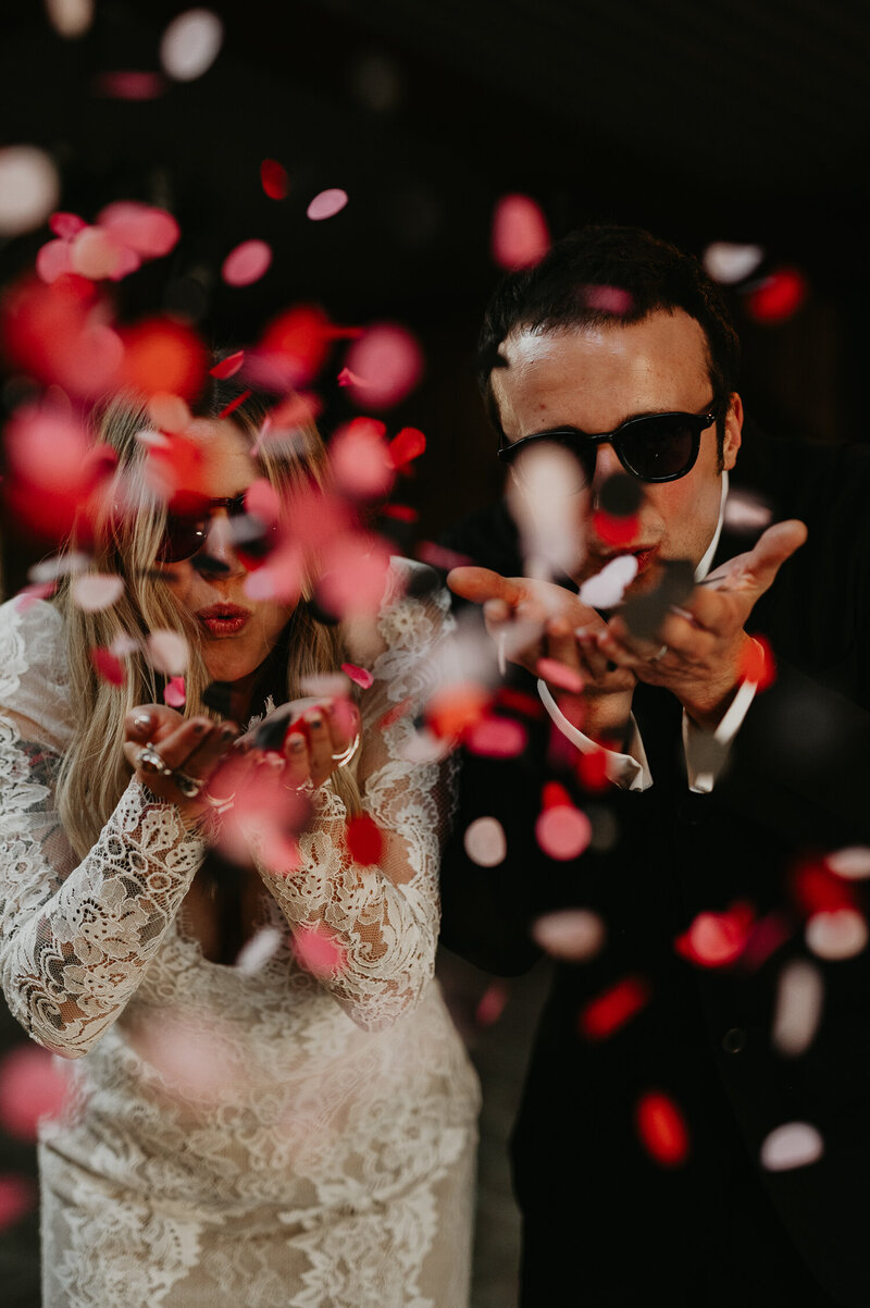 A bride and groom blow biodegradable wedding confetti.