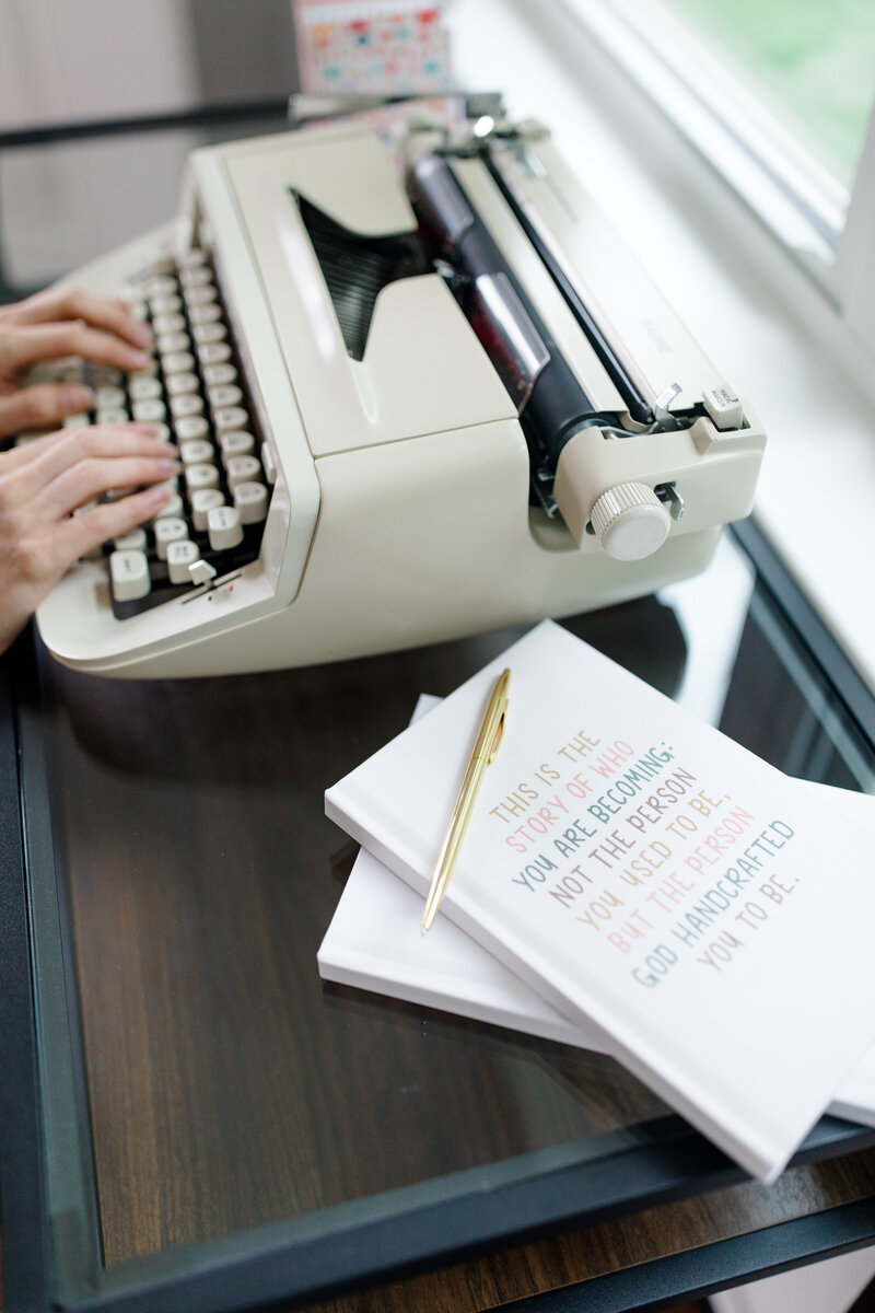 Women typing with a typewriter and journal 