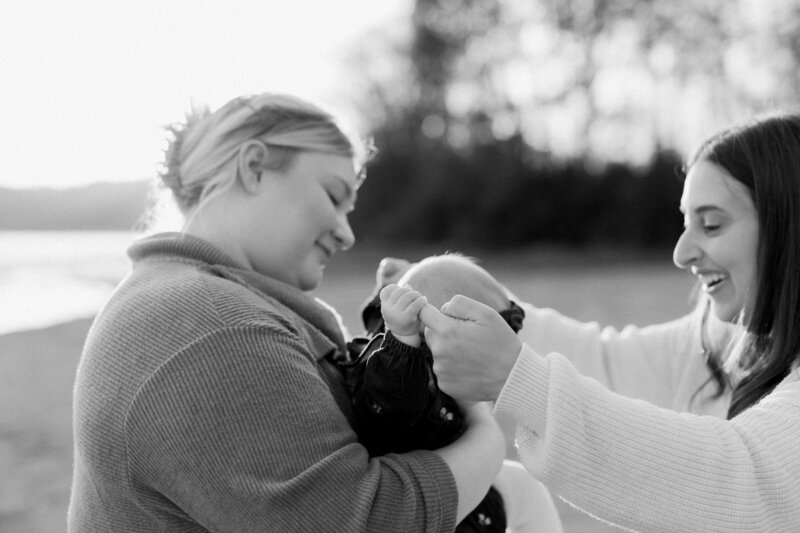 Two moms holding their baby's hands in black and white
