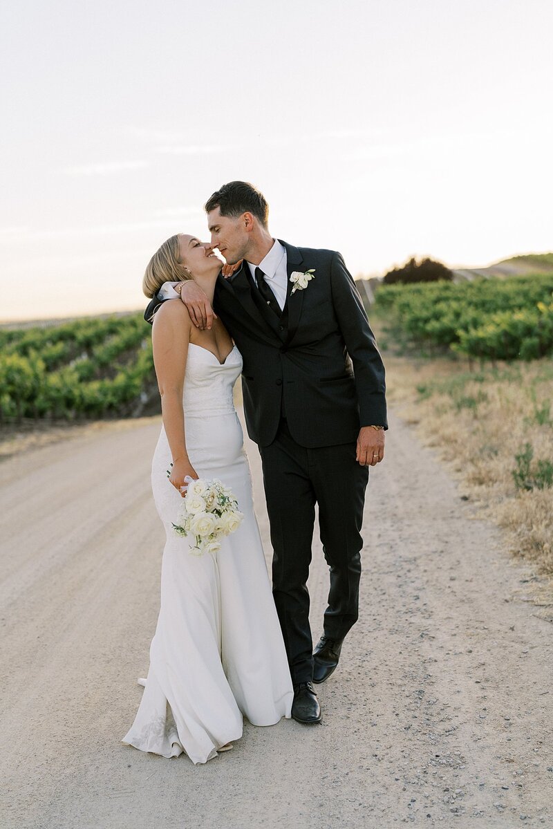 Bride and groom walking together in the vineyards at sunset in paso robles on their wedding day.