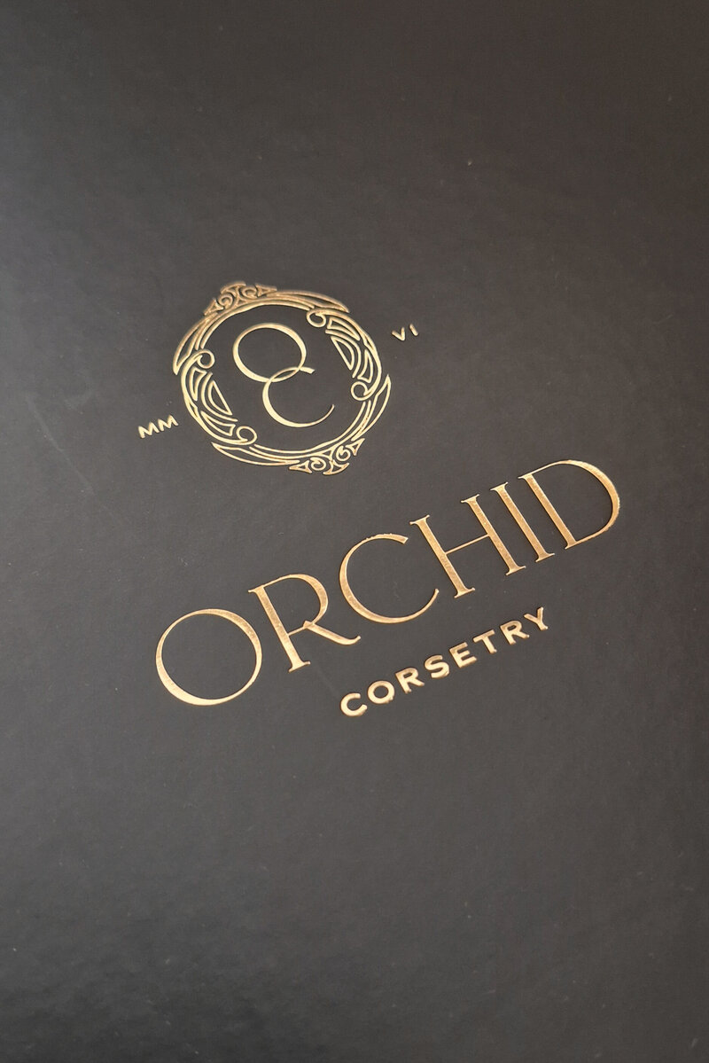 Gold foil Orchid Corsetry logo printed on a luxury black box
