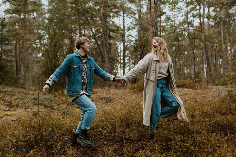 Two adult sisters walking hand in hand in a forest and laughing in Helsinki in Finland