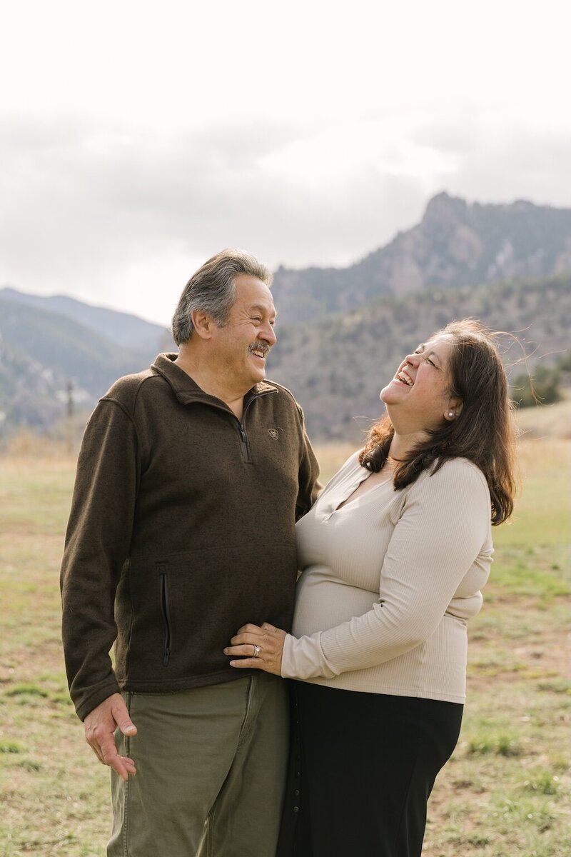 candid couple embracing and laughing in the mountains 