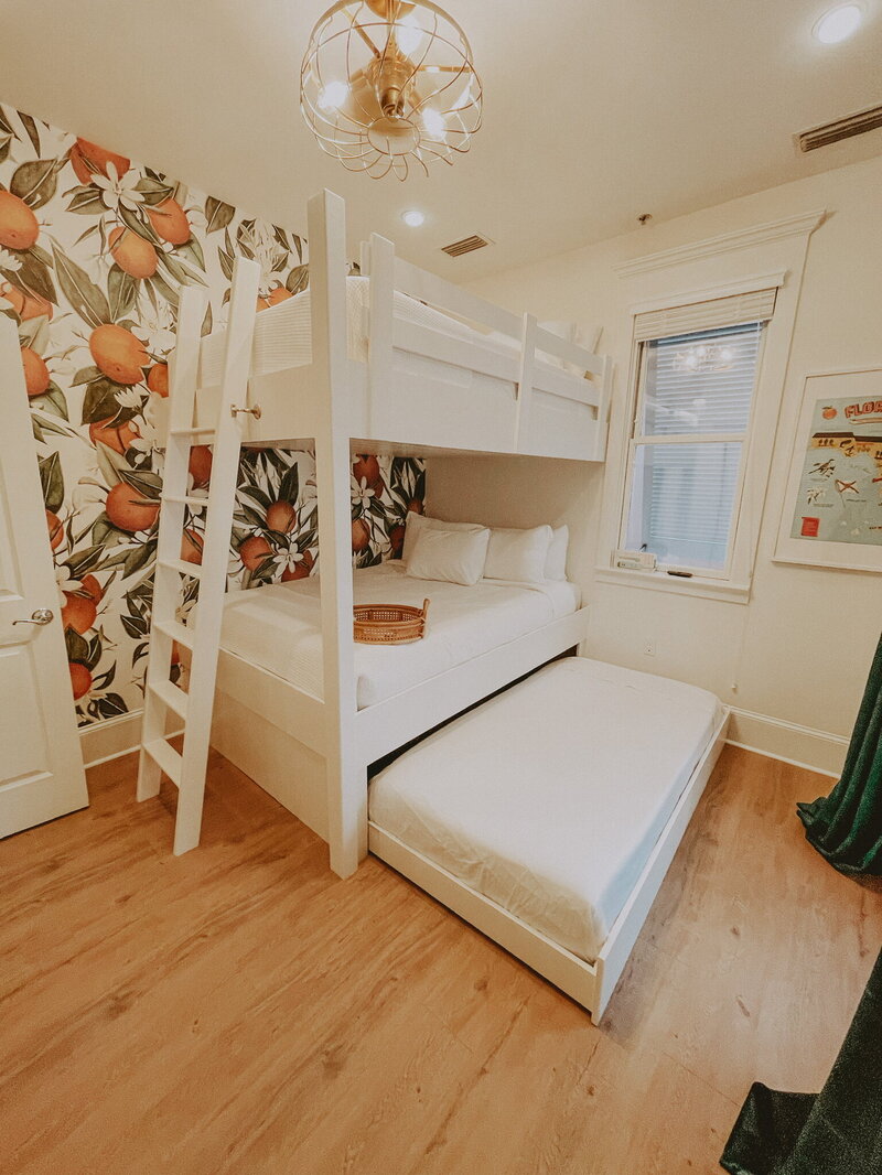 white bunk bed with trundle against wallpaper of oranges