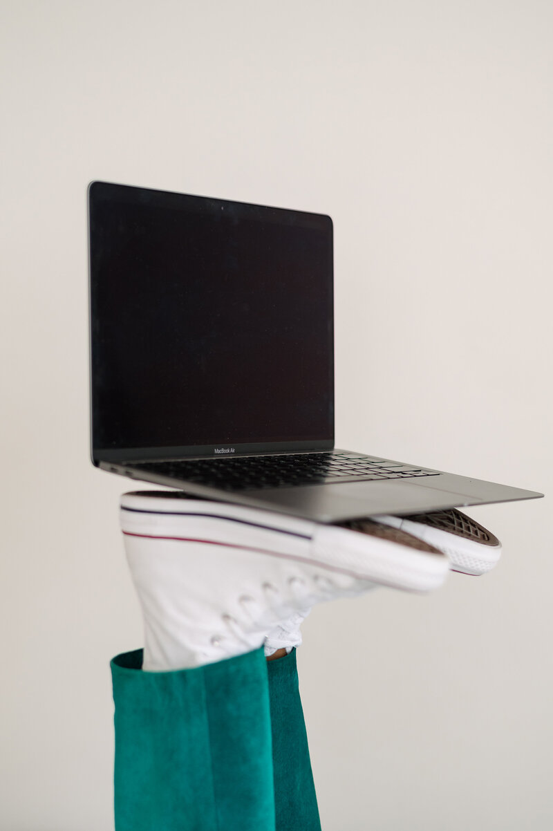 Photo of a women business owner holding a laptop on her feet