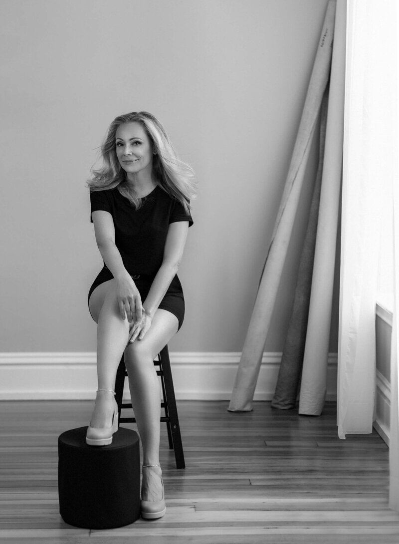 Black and white portrait of a smiling photographer with a camera.