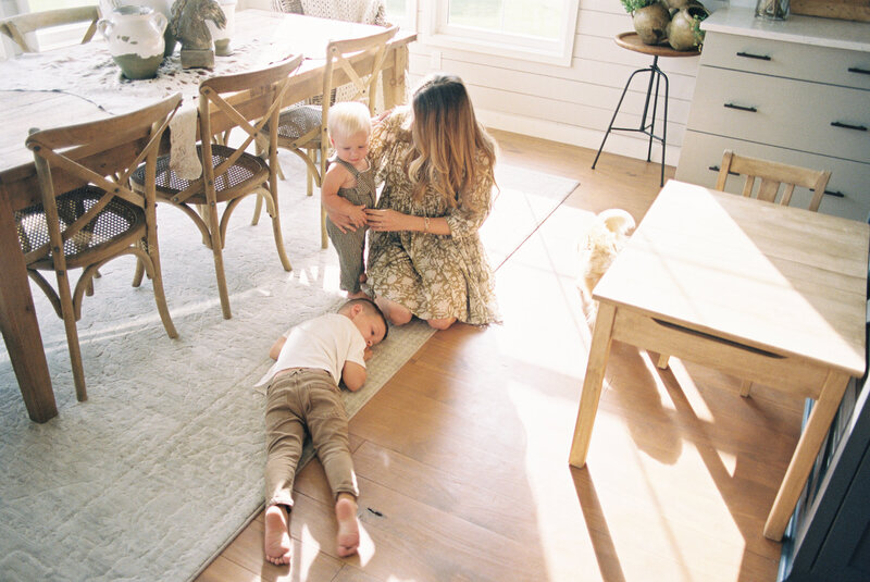 Mom sitting on the ground of a dining room with her two children