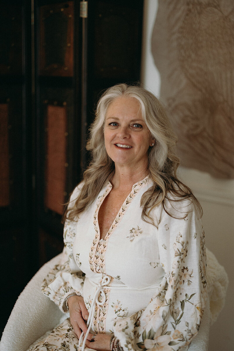 Janna Weldum of Eagle's Guiding Light sits in a chair smiling warmly at the camera.