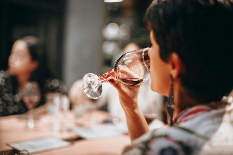 Image d'une femme qui boit un verre de vin rouge, lors d'une session de dégustation de vin.