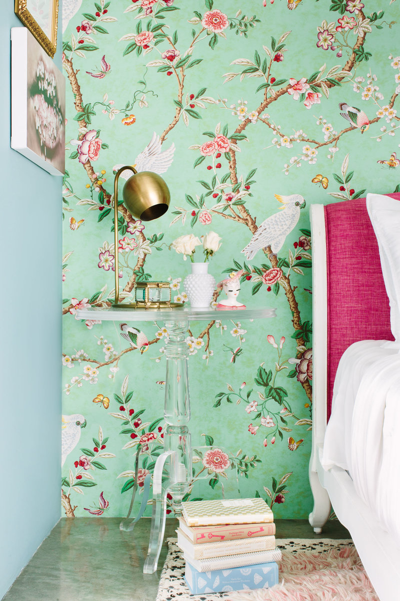 Bedroom with floral wallpaper, pink headboard, and Lucite acrylic nightstand