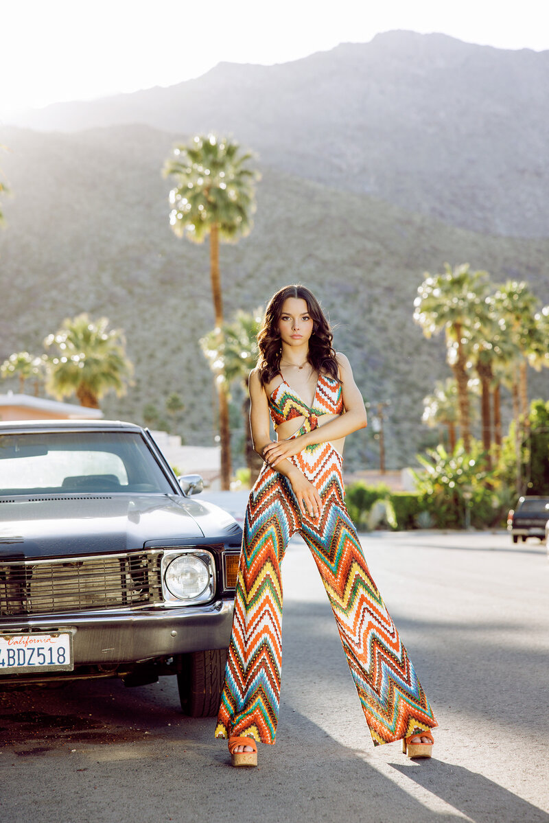 teen girl in elegant gown in desert setting with sun setting for senior portraits in Southern California