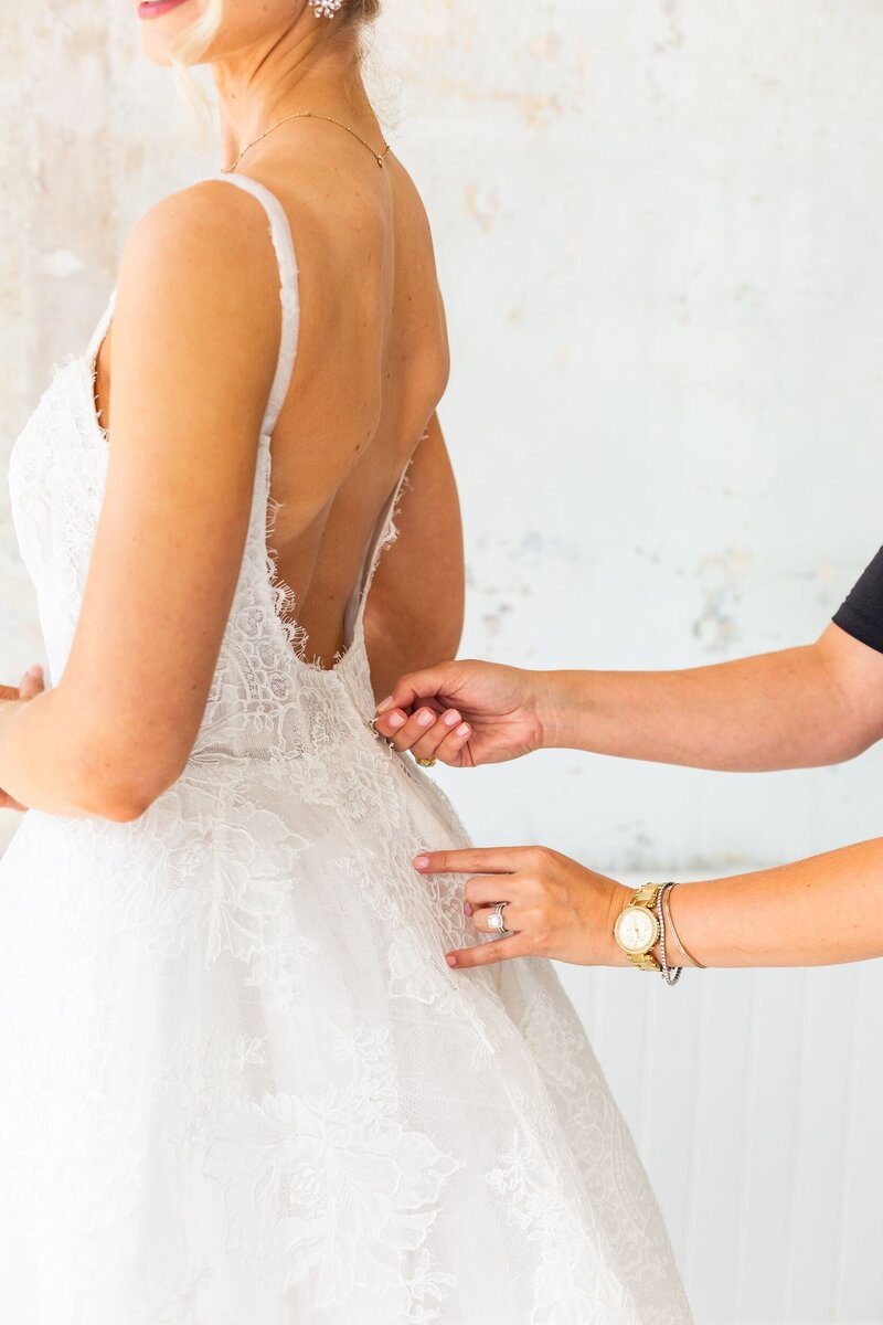 Stylist zipping bride into dress