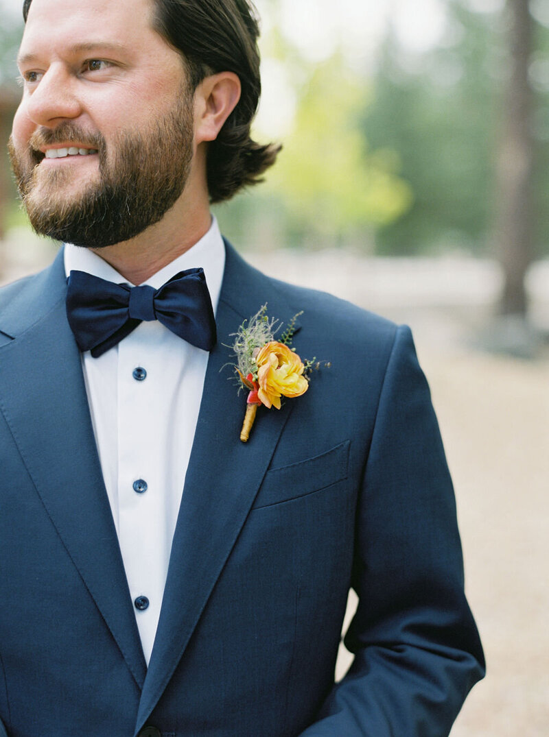 Groom Joe wearing a coral-toned boutonniere with seasonal floral accents and greenery, styled by Summer Robbins Flowers in Bend, Oregon