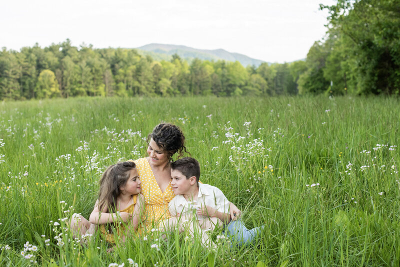 Mom and kids sitting in tall grass mountain views Asheville, NC family photography