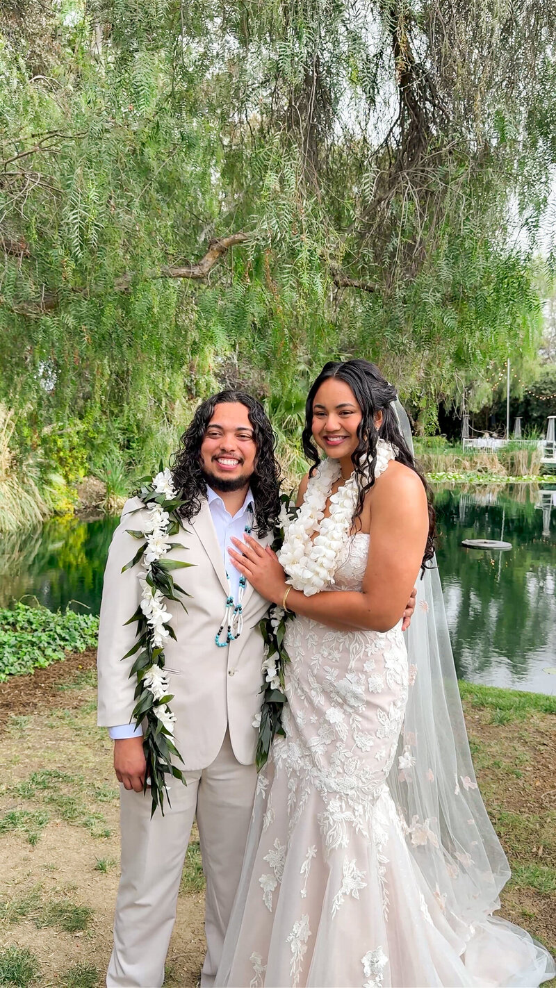 Bride and groom adorned in florals celebrating their wedding and taking portraits in front of the pond at The Orchard Wedgewood Weddings in Riverside.