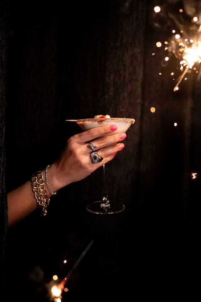 Martini glass being held up next to a sparkler