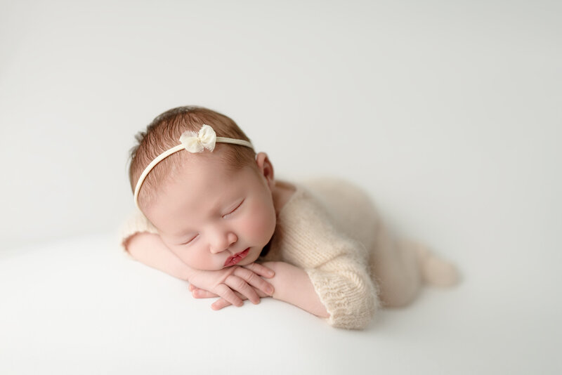 With her dainty bow and peaceful expression, this baby girl embodies the softness and grace of new life.
