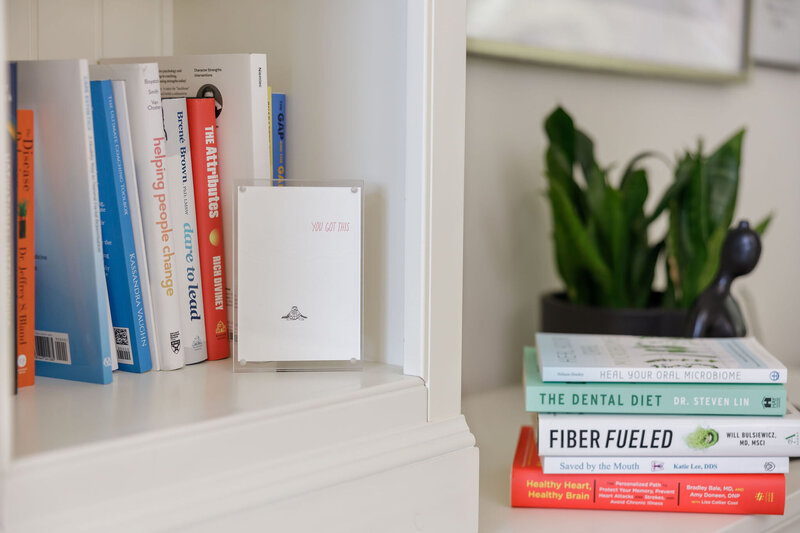 Stack of health-focused books including "The Dental Diet" and "Fiber Fueled" on functional health and oral care.