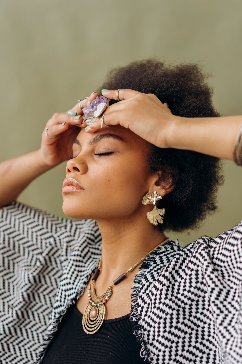 Woman closing her eyes and holding a crystal to her head