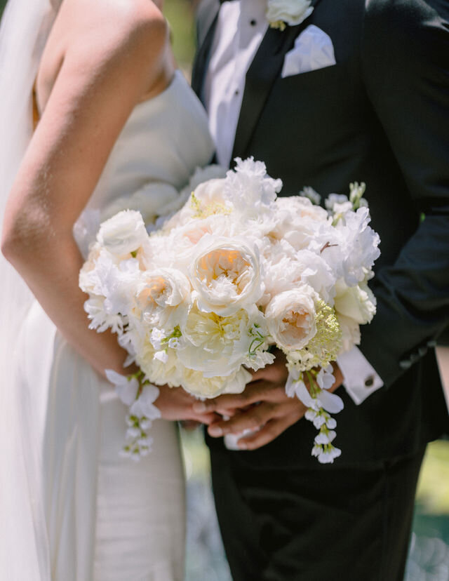 Newlywed couple holding a beautiful flower bouquet during their wedding ceremony. Photo by Get Ready Photo.
