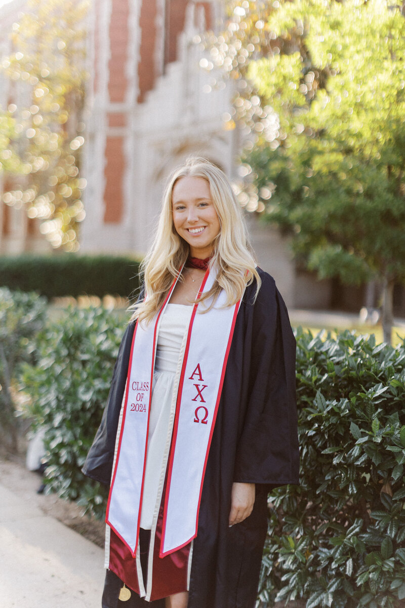 blonde girl in graduation regalia smiles in front of bizzell memorial library at the university of oklahoma - image by an ou senior photographer, melanie foster