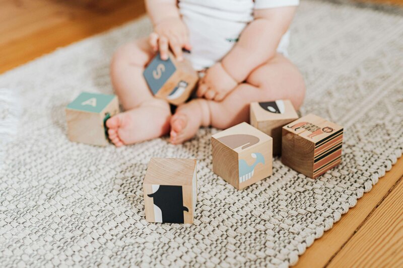 Baby sat on the floor with wooden blocks