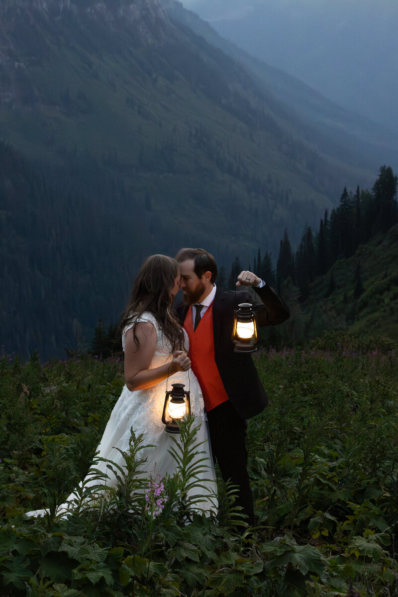 Couple facing each other holding lanterns during blue hour Glacier National Park.
