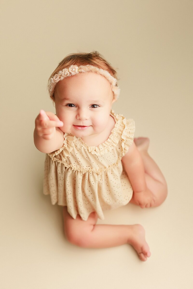 Baby girl wearing oversized bow headband during styled milestone session