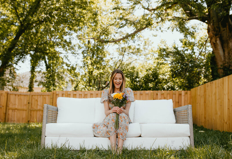 woman looking down at flowers smiling