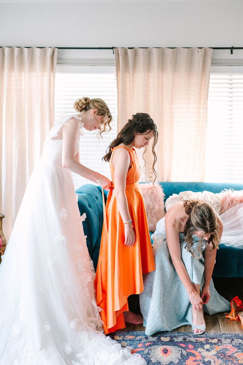 Bride helping bridesmaids get ready at colorful vibrant LGBTQ DFW wedding 