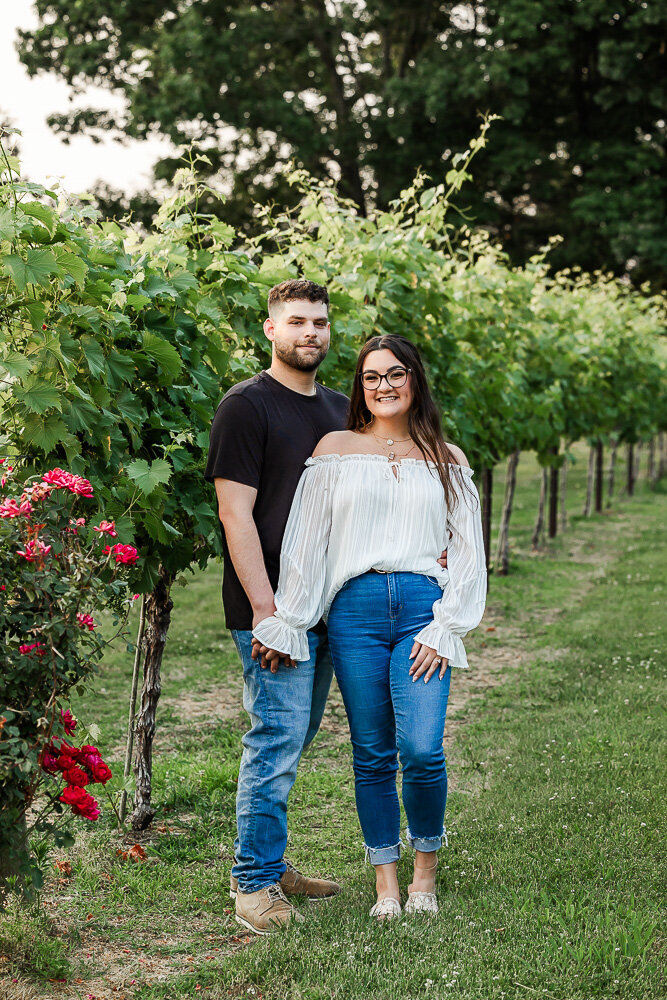 Couple holding hands in front of vineyard trees