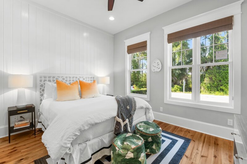 Light-filled queen bedroom with tropical accents and large windows in a 30A vacation rental near Panama City Beach.
