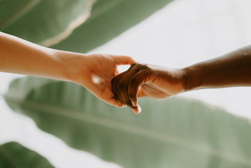Close-up of interracial couple holding hands at wedding
