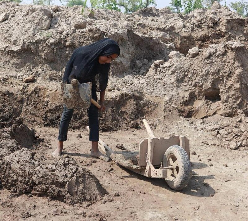 An enslaved young child works at the kiln gathering dirt for the bricks.