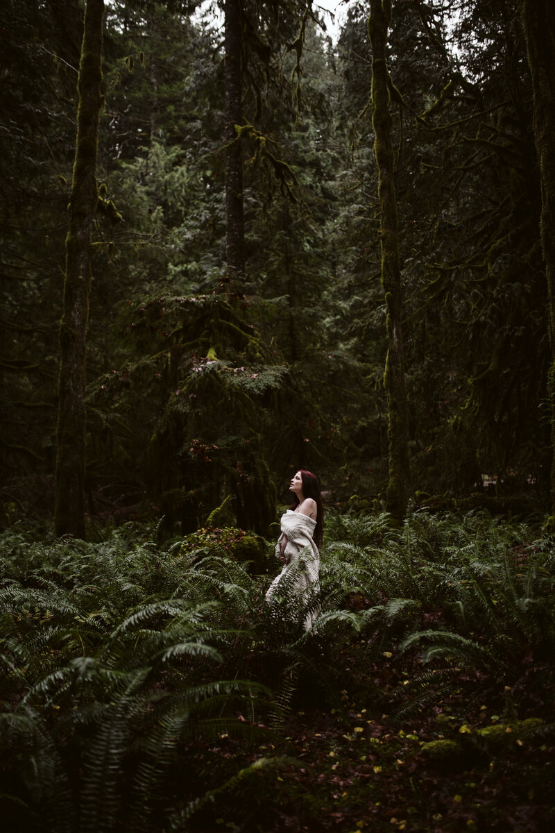 Bride walking alone through a lush green forest, evoking serenity, captured by an Oregon Coast Elopement and Wedding Photographer.